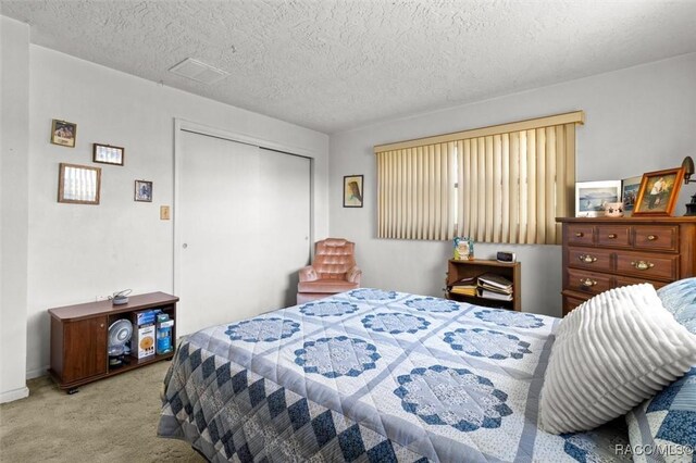 carpeted bedroom featuring visible vents, a closet, and a textured ceiling