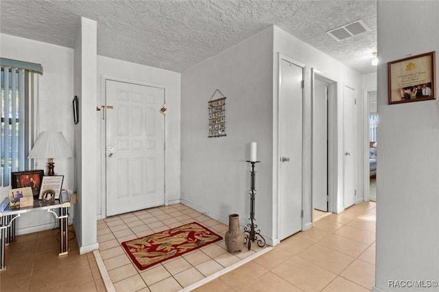 tiled foyer entrance featuring visible vents and a textured ceiling