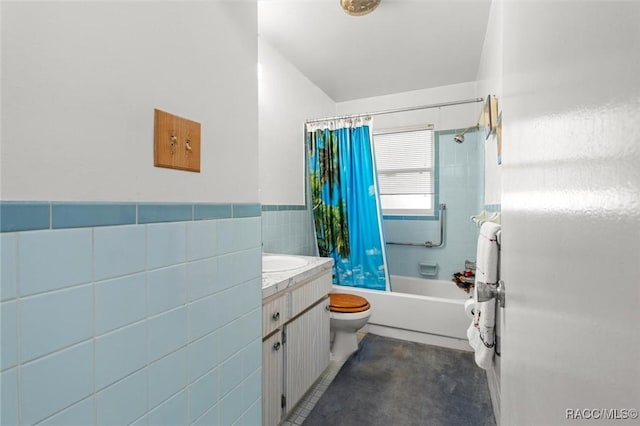 full bathroom with tile walls, a wainscoted wall, toilet, shower / bath combo with shower curtain, and vanity