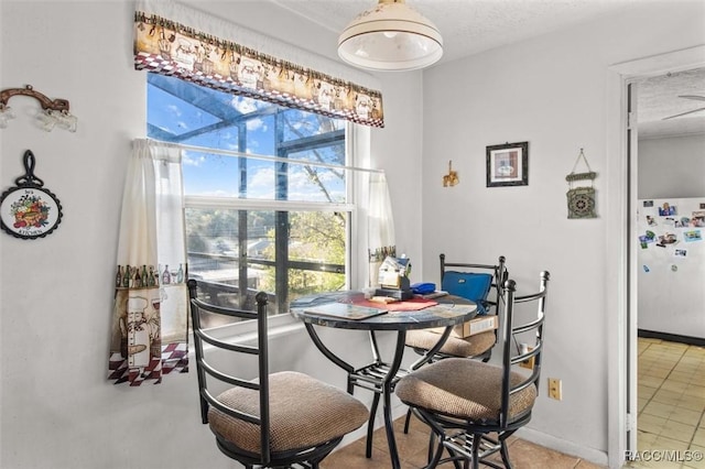 dining room featuring a textured ceiling and baseboards