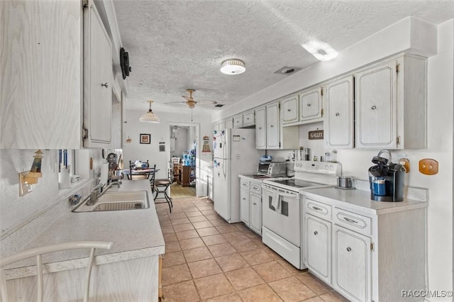 kitchen featuring a sink, white appliances, a textured ceiling, and light countertops