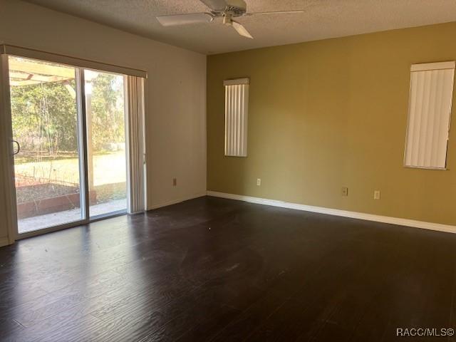 spare room with ceiling fan, dark hardwood / wood-style floors, and a textured ceiling