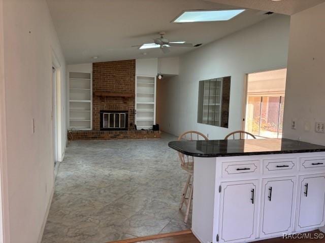 kitchen featuring lofted ceiling, white cabinetry, a kitchen breakfast bar, built in shelves, and kitchen peninsula