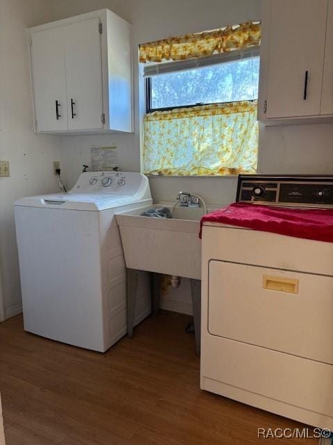 laundry area featuring cabinets, hardwood / wood-style floors, and washer and dryer