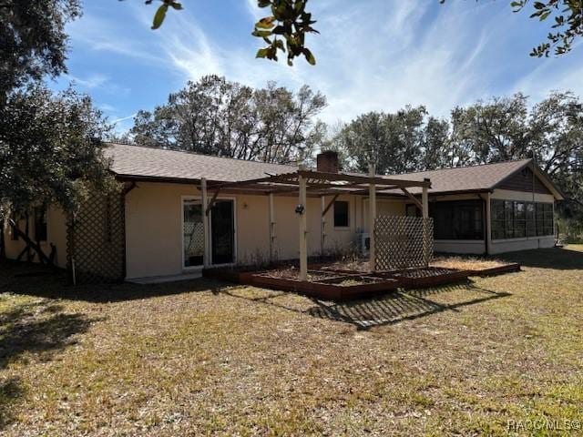 rear view of property with a yard and a sunroom