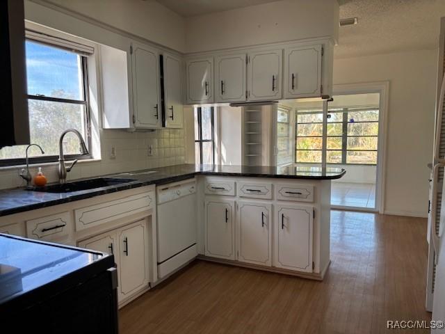 kitchen with sink, white cabinets, white dishwasher, and kitchen peninsula