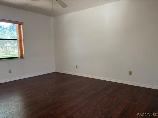 empty room with ceiling fan, dark hardwood / wood-style flooring, and a textured ceiling