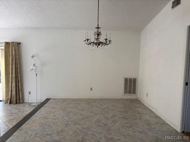 unfurnished dining area with a chandelier and a textured ceiling