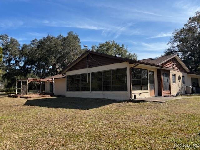 rear view of property with a sunroom and a lawn