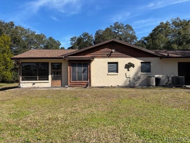 back of house with cooling unit and a yard