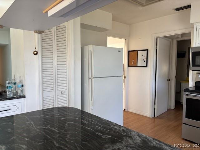 kitchen featuring stainless steel appliances, light hardwood / wood-style flooring, and white cabinets