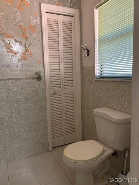 bathroom featuring tile walls, tile patterned floors, and toilet