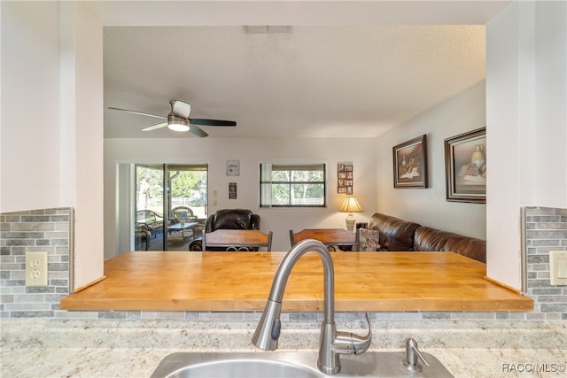 kitchen featuring butcher block countertops, ceiling fan, sink, and a textured ceiling