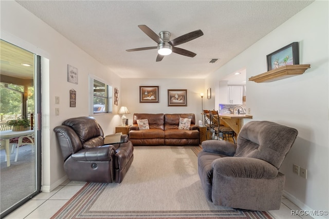 living room with light tile patterned flooring, a textured ceiling, a wealth of natural light, and ceiling fan