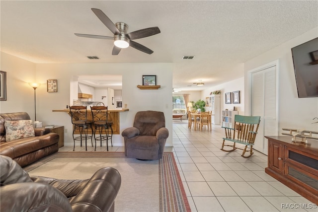 tiled living room with ceiling fan and a textured ceiling