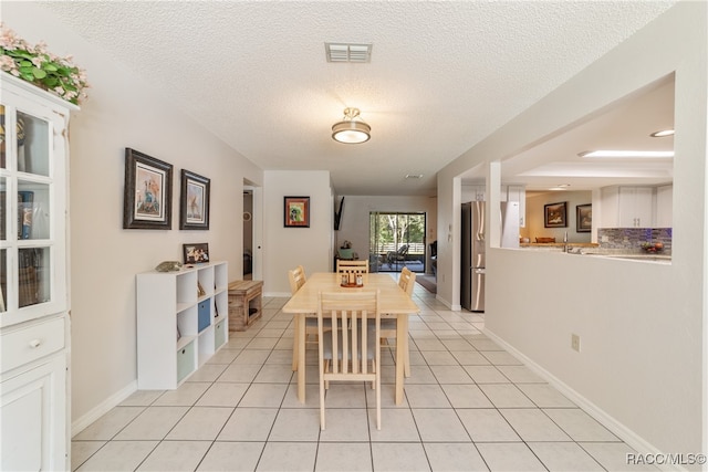 tiled dining area featuring a textured ceiling