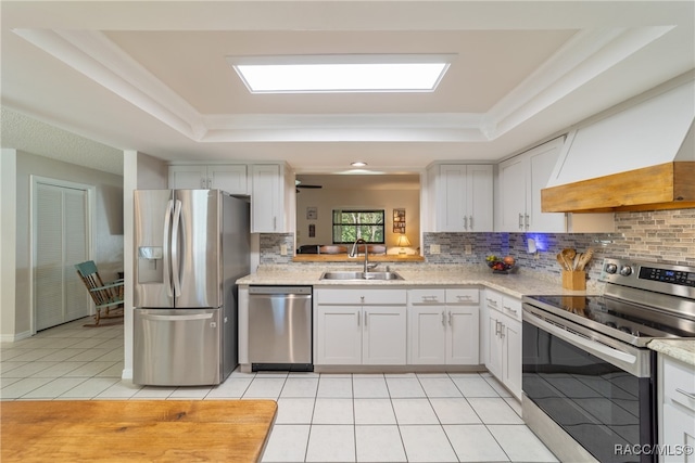 kitchen with sink, custom range hood, appliances with stainless steel finishes, tasteful backsplash, and white cabinetry