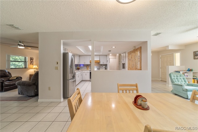 tiled dining room with ceiling fan and a textured ceiling