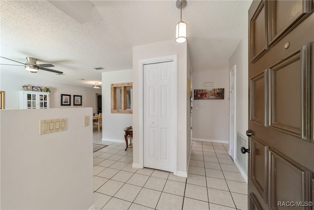 hall featuring light tile patterned flooring and a textured ceiling