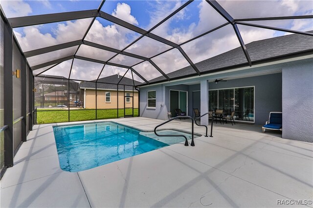 view of pool featuring glass enclosure, ceiling fan, and a patio area