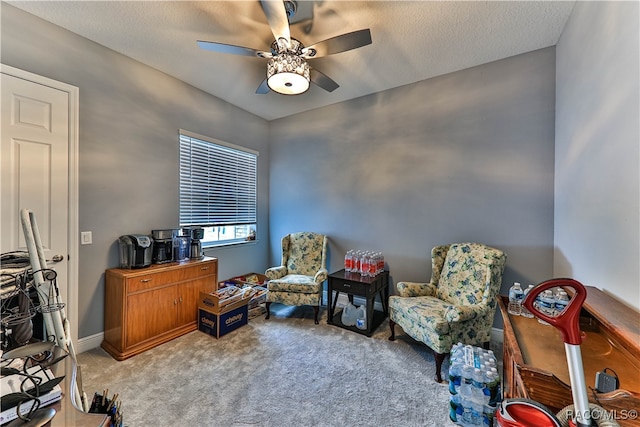 living area featuring ceiling fan, light colored carpet, and a textured ceiling