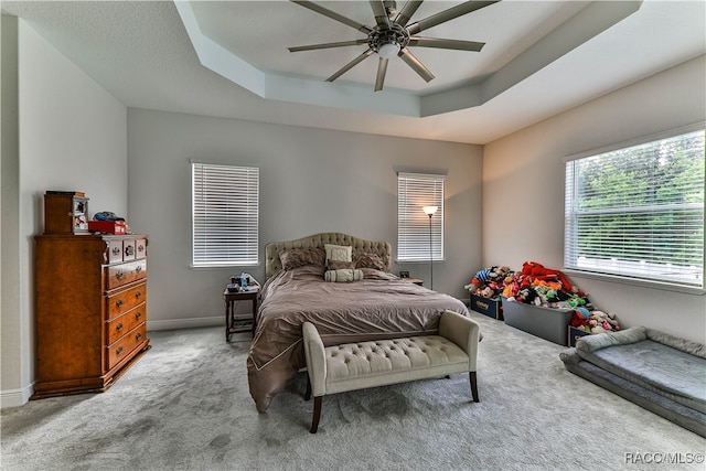 carpeted bedroom featuring ceiling fan and a raised ceiling