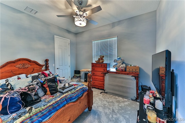 bedroom with ceiling fan, light colored carpet, and a textured ceiling