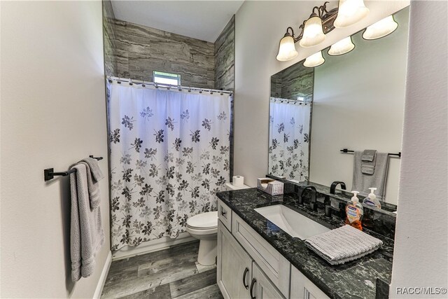 full bathroom featuring shower / bath combo with shower curtain, hardwood / wood-style floors, vanity, and toilet