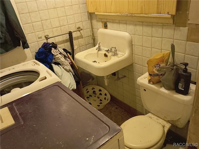 bathroom featuring washer / dryer, tile walls, and sink