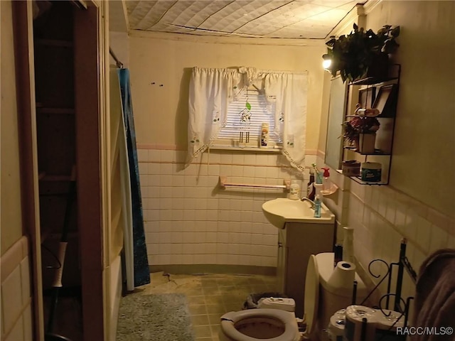 full bathroom with shower / bathtub combination with curtain, tile patterned floors, toilet, vanity, and tile walls