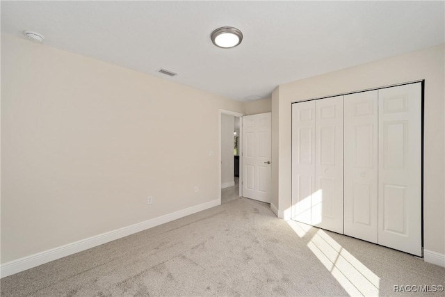 unfurnished bedroom featuring a closet and light colored carpet