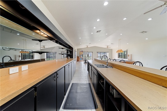 kitchen featuring ceiling fan, vaulted ceiling, hanging light fixtures, and sink