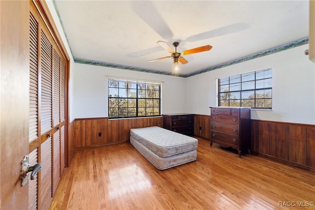 bedroom featuring light hardwood / wood-style flooring, ceiling fan, and wood walls