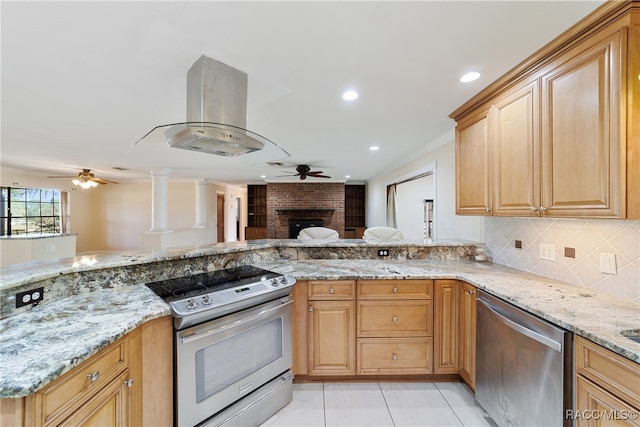 kitchen featuring light tile patterned floors, a fireplace, appliances with stainless steel finishes, island range hood, and light stone counters