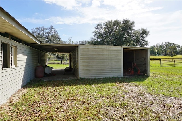 view of outdoor structure with a rural view and a lawn