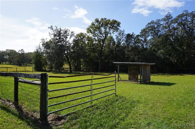 view of gate with a yard and a rural view