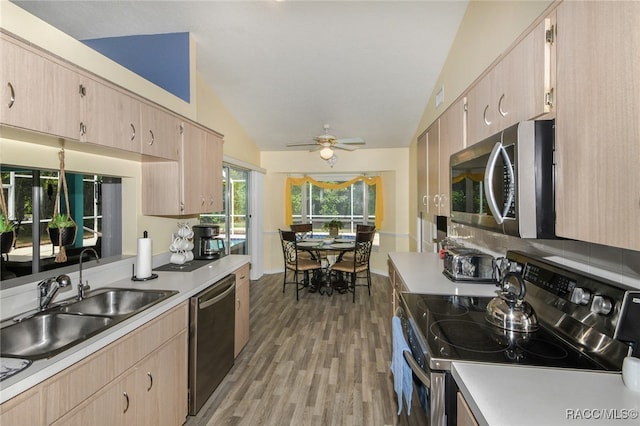 kitchen featuring lofted ceiling, sink, light hardwood / wood-style flooring, ceiling fan, and appliances with stainless steel finishes