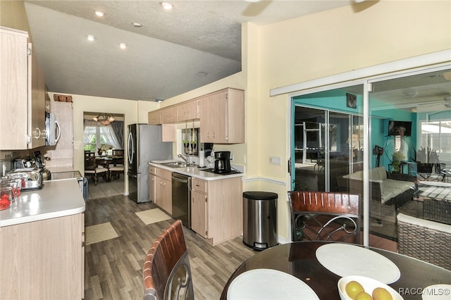 kitchen featuring sink, light brown cabinets, stainless steel appliances, hardwood / wood-style floors, and vaulted ceiling