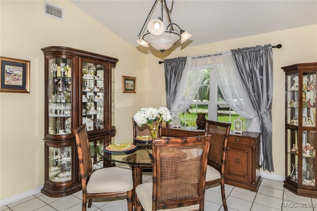 dining space with light tile patterned flooring and vaulted ceiling