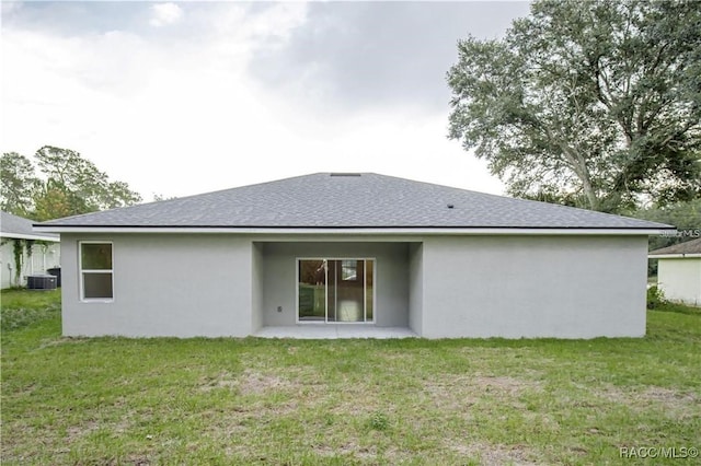 rear view of house featuring a lawn and central AC unit