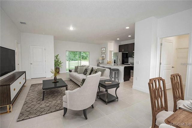 living room featuring sink and light tile patterned floors