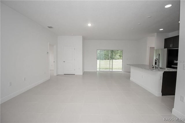 unfurnished living room with light tile patterned floors and sink