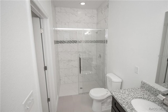 bathroom featuring vanity, a shower with shower door, and toilet