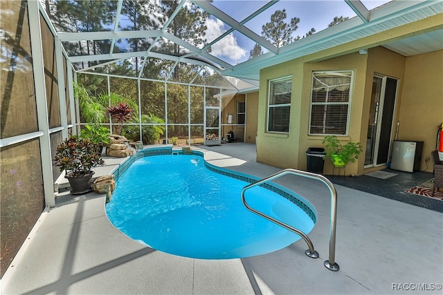 view of swimming pool with glass enclosure and a patio