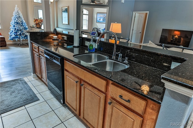 kitchen featuring ceiling fan, dishwasher, sink, dark stone counters, and light tile patterned floors