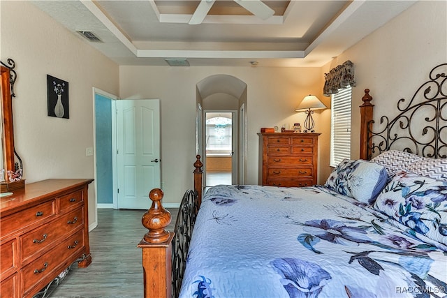 bedroom with a raised ceiling, ceiling fan, and hardwood / wood-style flooring