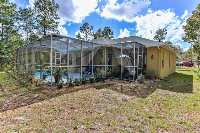 back of house featuring a patio area, a lanai, and a yard