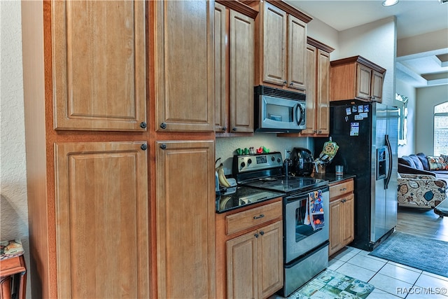 kitchen with light tile patterned floors, stainless steel appliances, and dark stone counters