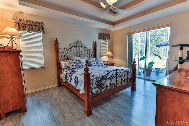 bedroom with a raised ceiling, ceiling fan, dark hardwood / wood-style floors, and access to outside