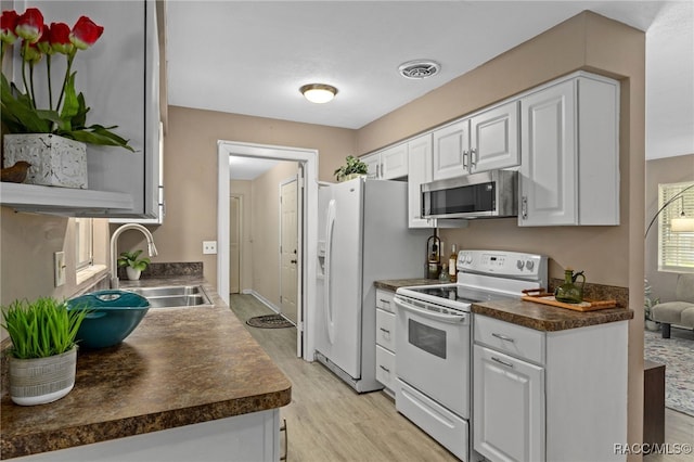4 S Columbus St, Beverly Hills, FL 34465 - kitchen featuring electric range, light wood finished floors, dark countertops, white cabinetry, and stainless steel microwave